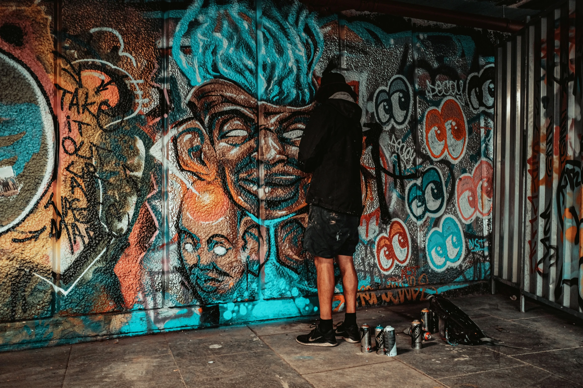 person wearing black shoes standing on floor near wall covered with graffiti