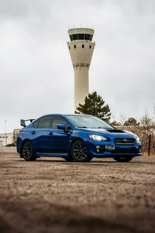 a subaru that is sitting in the dirt near a control tower