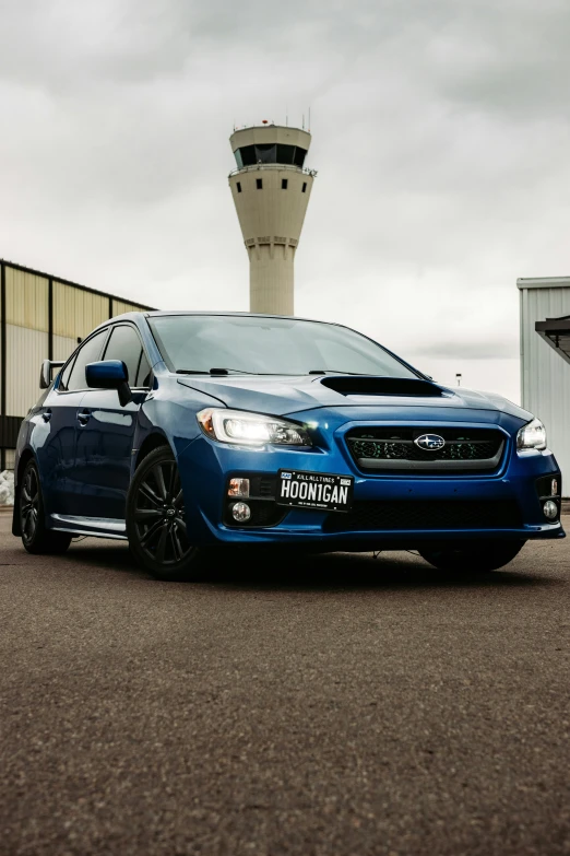 blue subarun car parked in front of an airport control tower