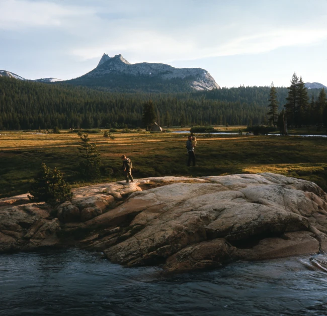 some people stand on a rock near a river