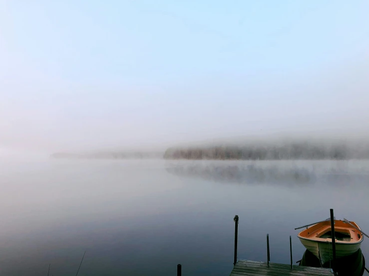 misty morning fog over a boat tied to a dock