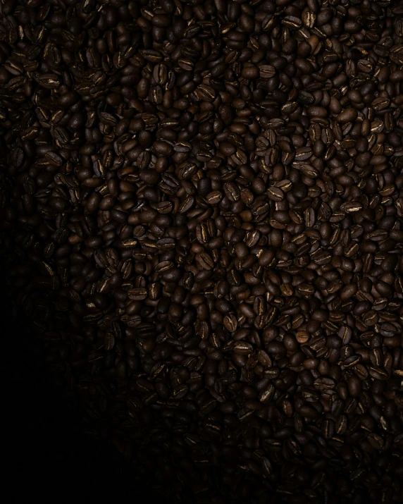 some brown coffee beans on a black table