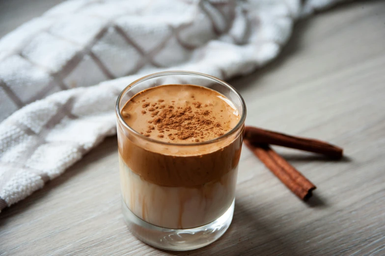 a glass of iced coffee sitting on top of a wooden table