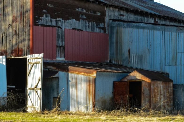 an old metal grain silo and barn in an open field