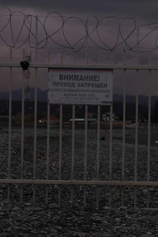 a sign is behind bars that are near a barbed wire fence