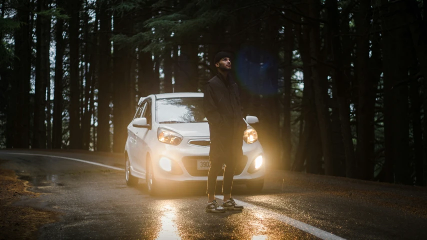 a man in black standing next to a white car