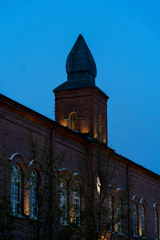 a large building has a steeple lit up at night