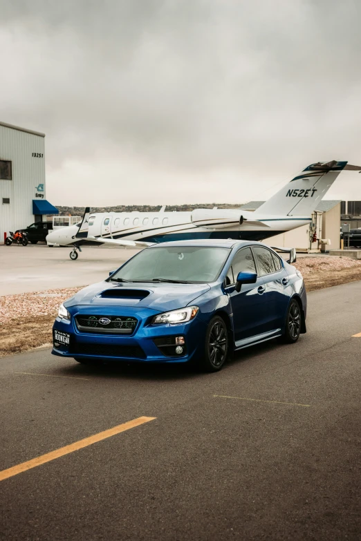 blue sports car parked near an airplane at the airport