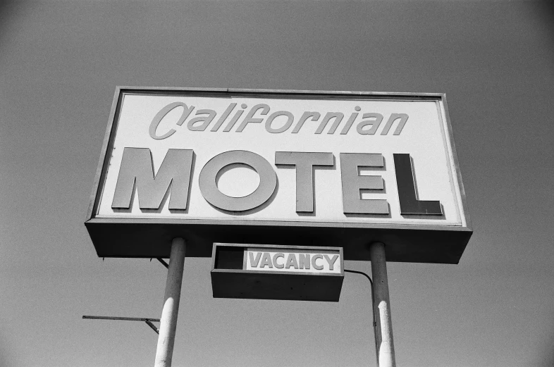 a motel sign is standing in front of a gray sky