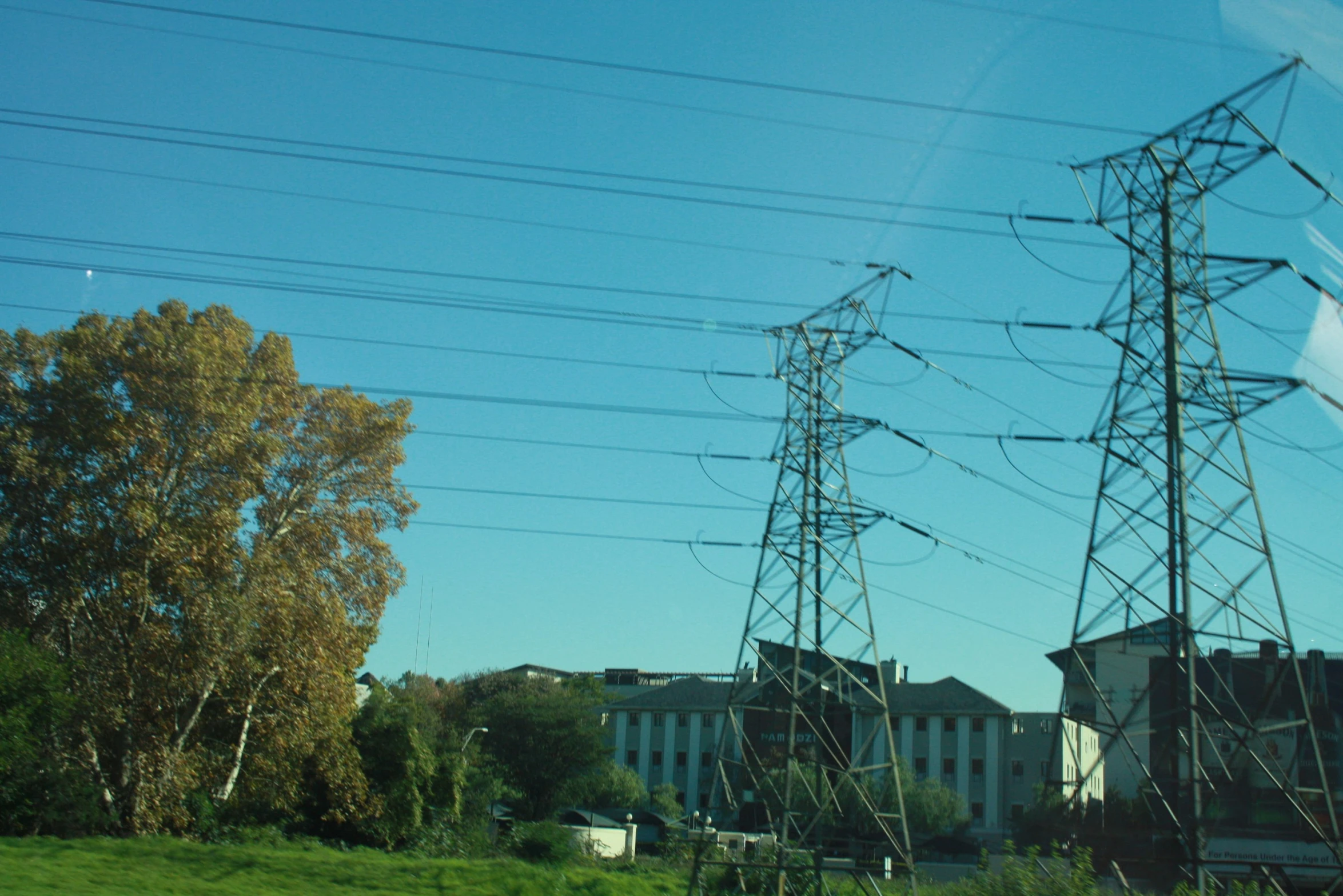 an electric tower with power lines and a building in the background