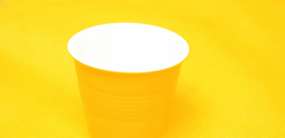 a plastic cup sitting on top of a yellow table