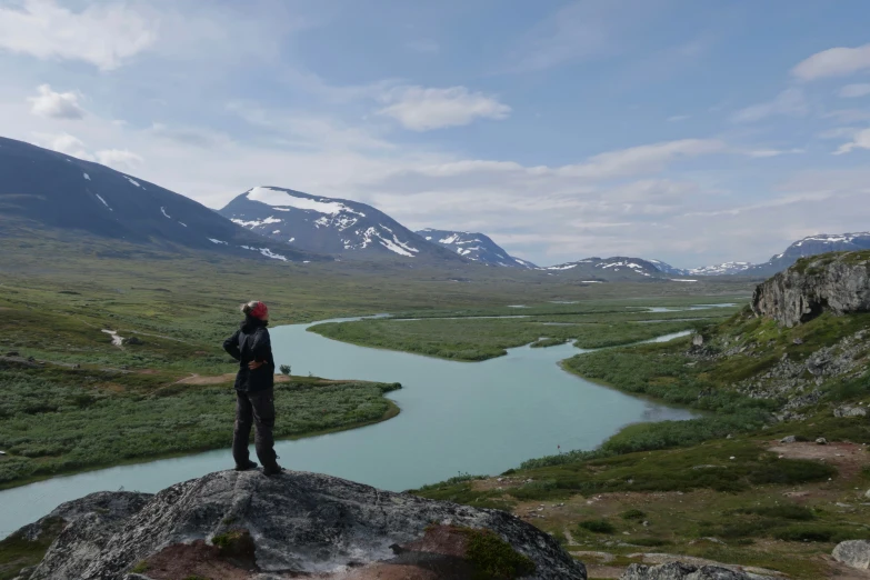 a person standing on top of a rocky cliff next to a river