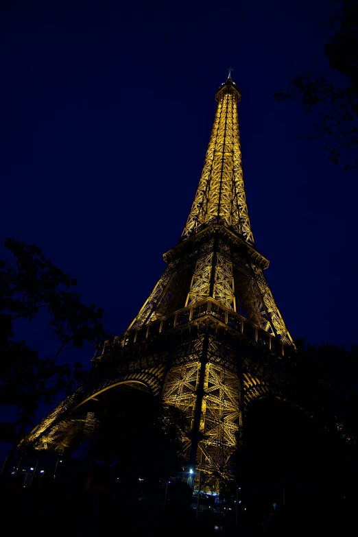 night time s of the eiffel tower lit up with yellow lights