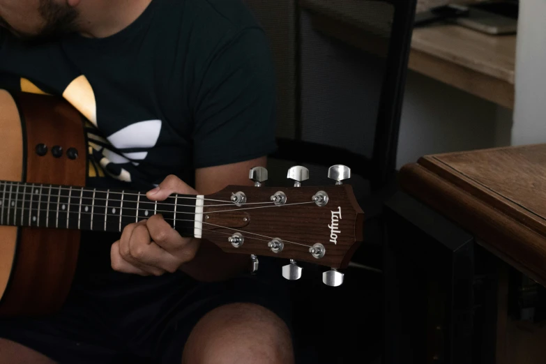 a man playing a guitar while sitting down on a chair