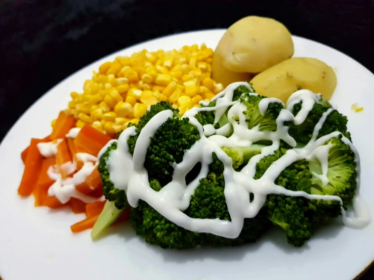 a plate of vegetables and potatoes covered in dressing