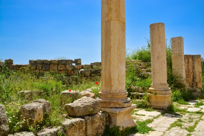 a few pillars in a green area in front of rocks