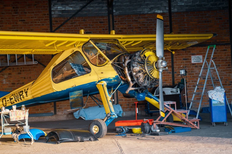 a yellow and blue airplane is being worked on