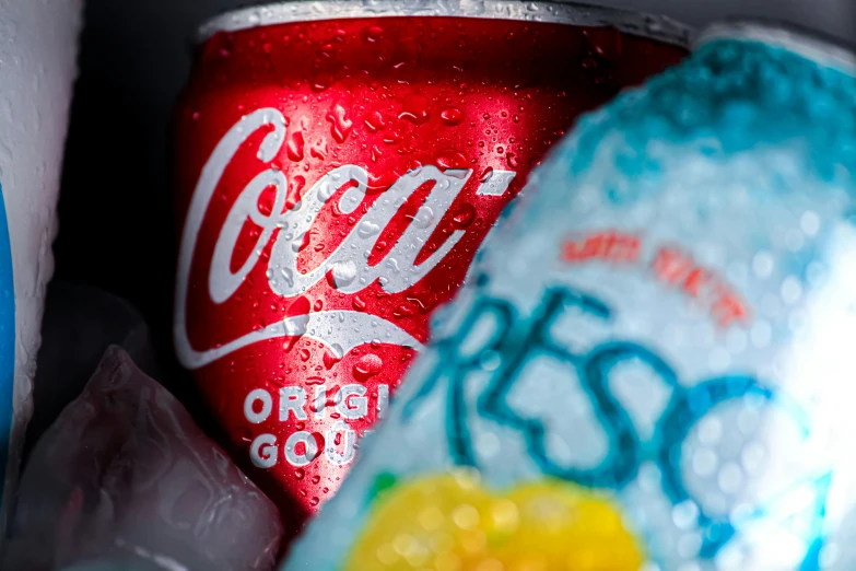 two cokes next to a can in front of bags