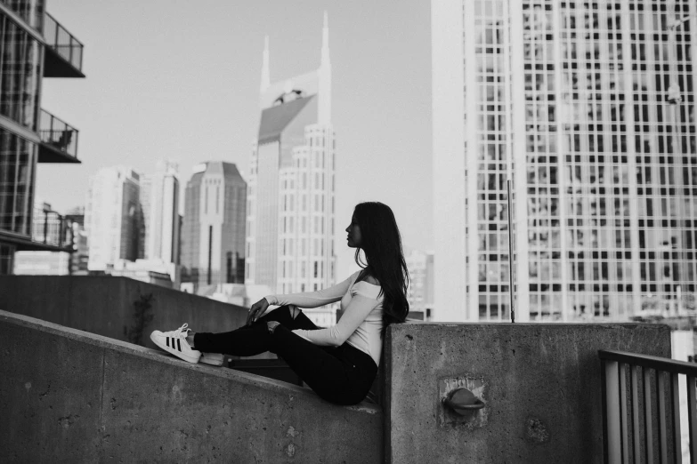 a girl sitting on a ledge looking out over the city