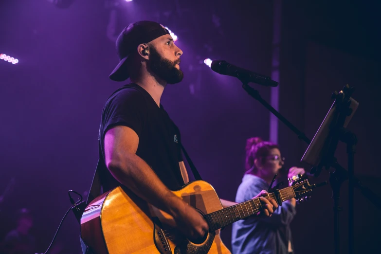 a man with a beard is holding an acoustic guitar