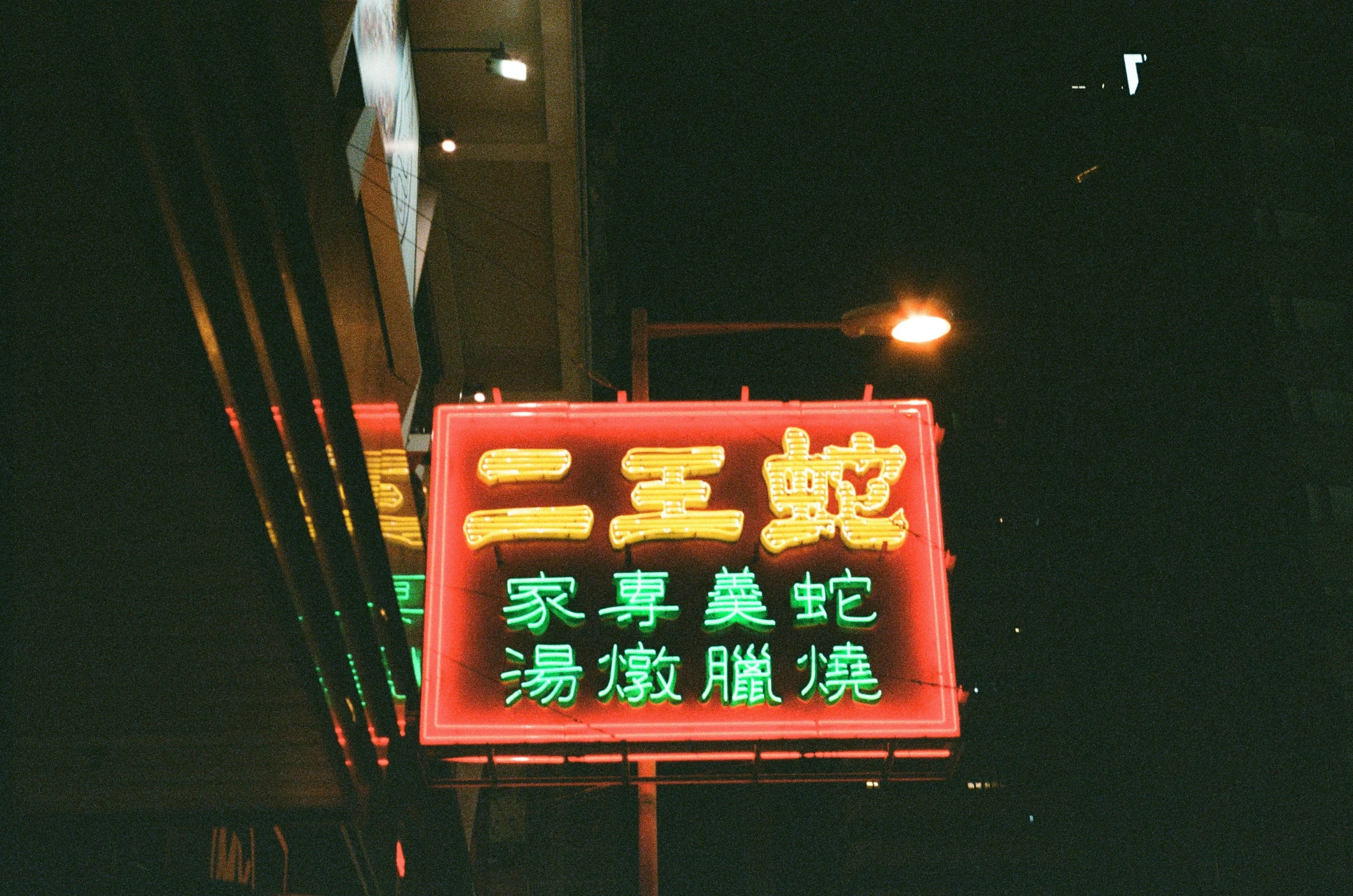 a red neon sign sitting on the side of a road