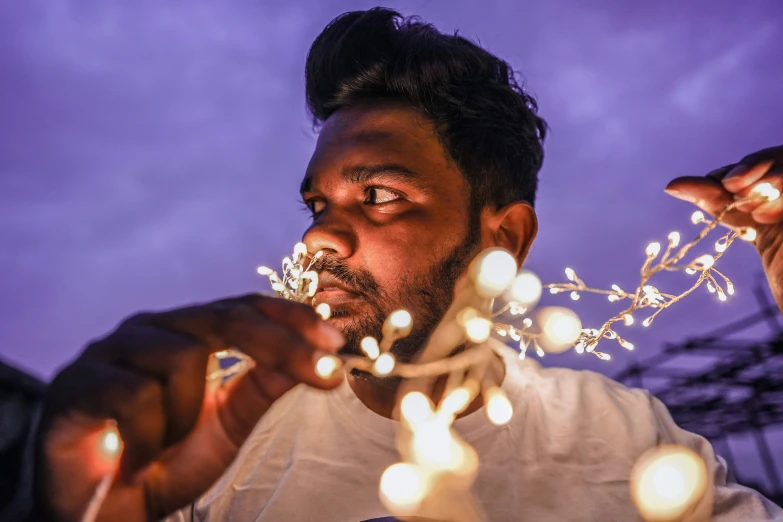 a man holds up a string of lights above his face