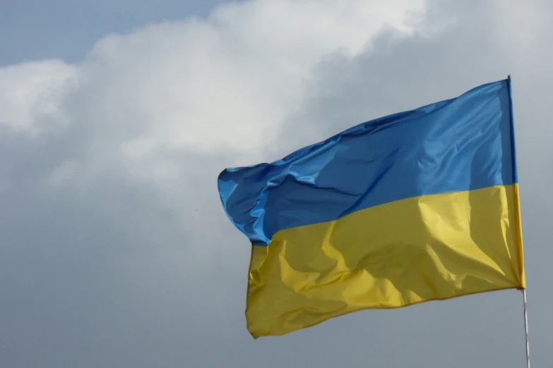 a flag flying in the air on top of a cloud filled sky