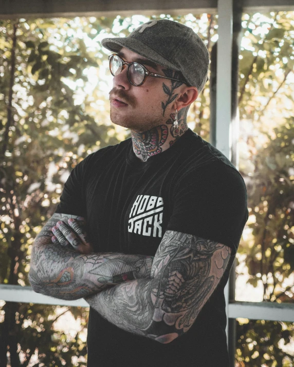 a tattooed man standing with his arms crossed