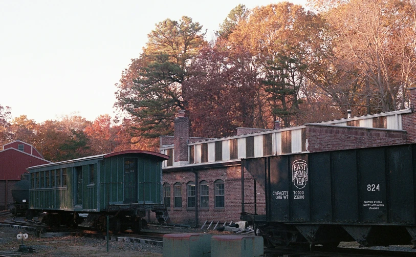 train cars parked on the tracks at an old building