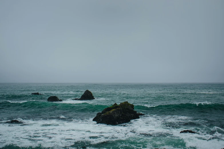 the ocean on a cloudy day with rocky shoreline