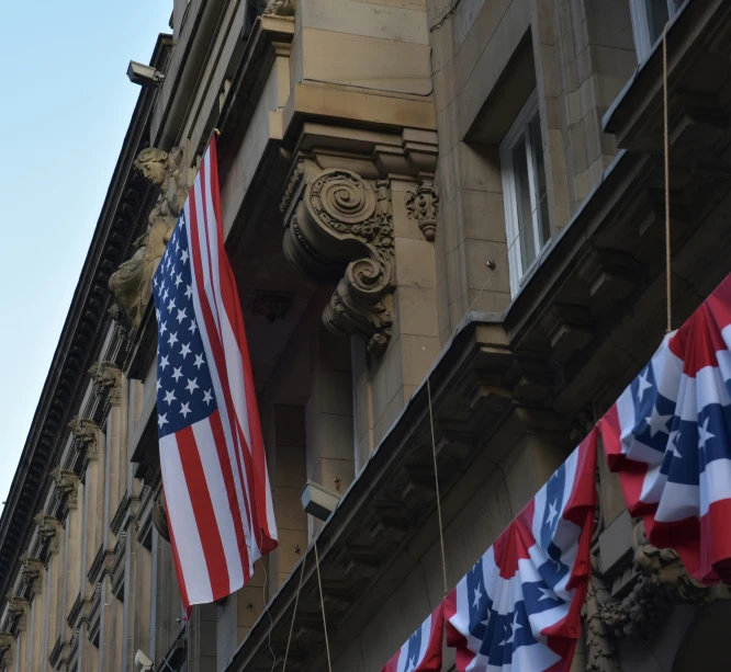 two flags on a string next to an old building