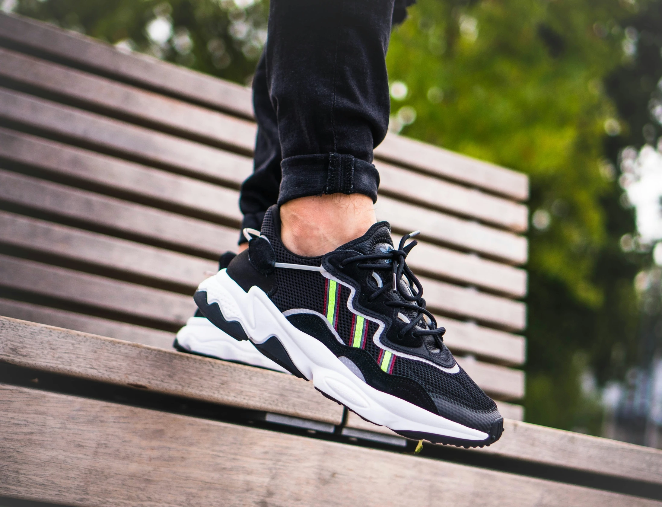 black and white sneakers on a wooden park bench