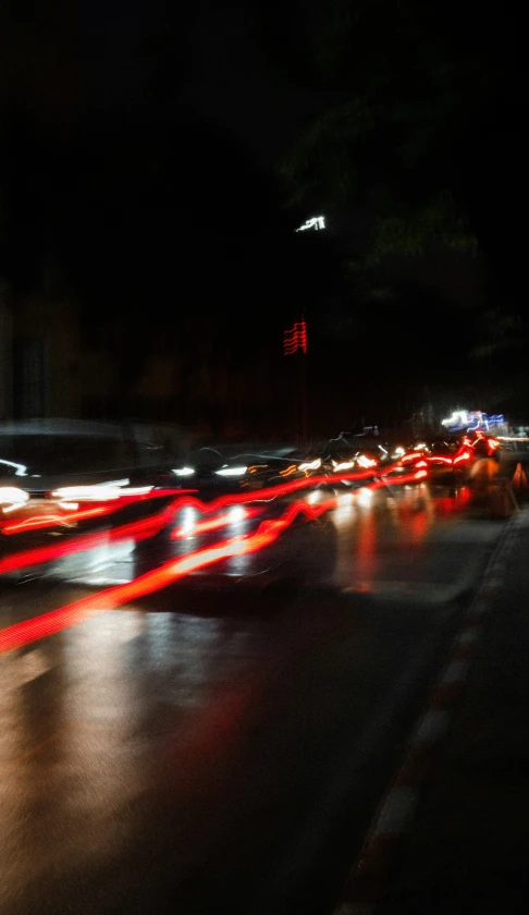 car lights streaking down the middle of a street at night