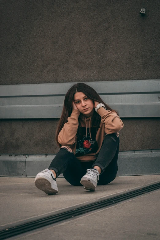 a young woman sitting on the ground near a train track