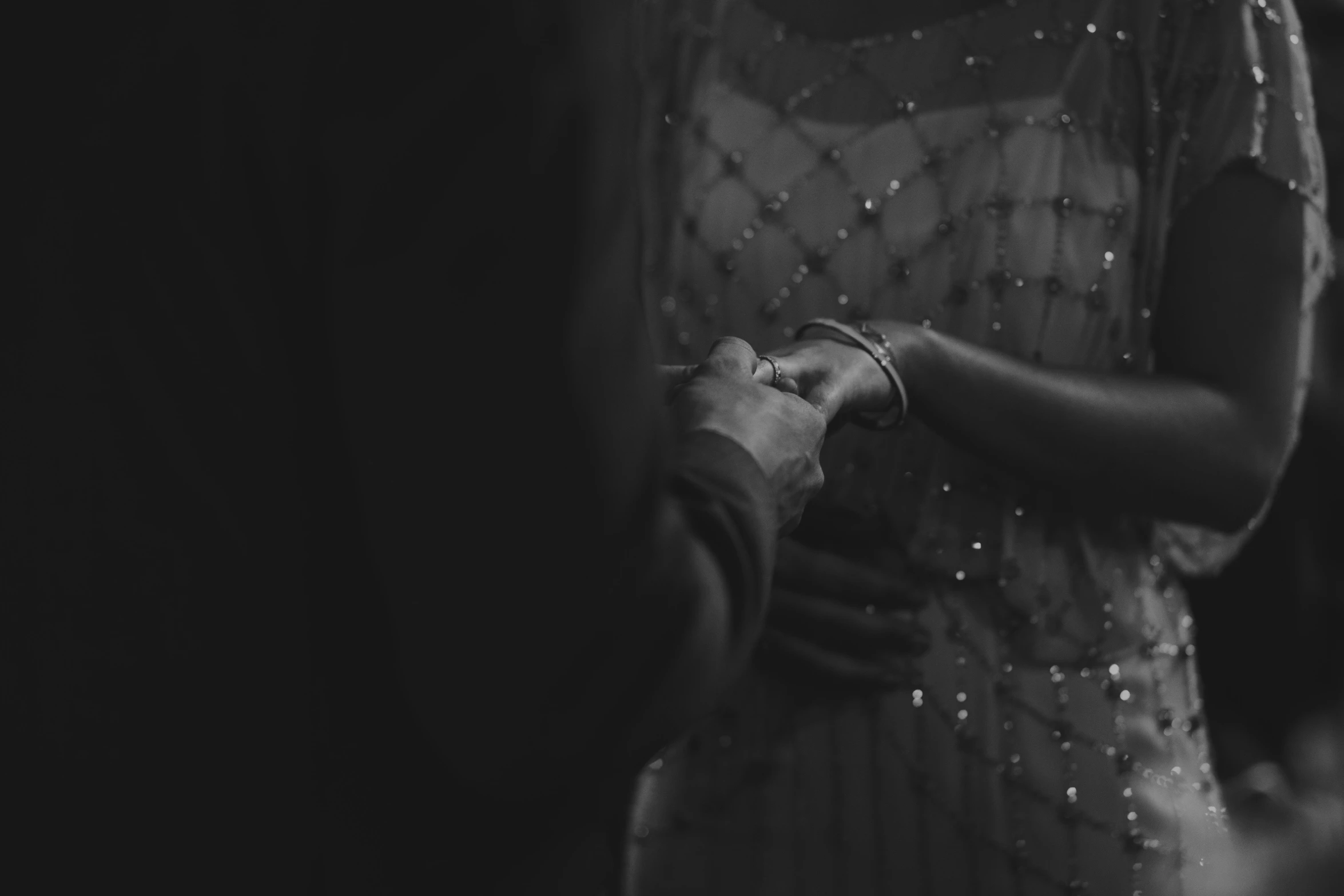 a woman holding the hands of another man with pearls on his dress