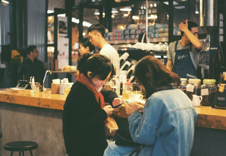 several people in a bar that is holding their cellphones