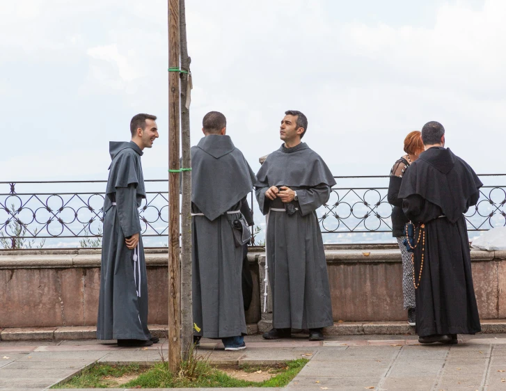 four people wearing medieval clothing standing on a bridge