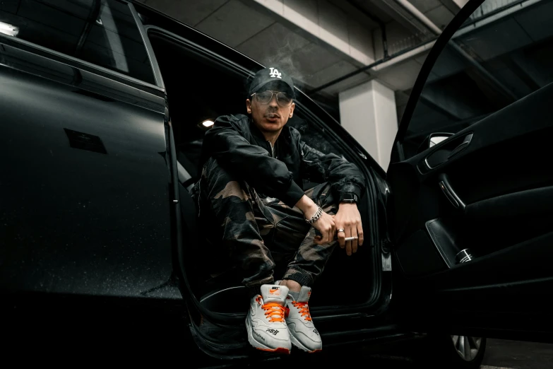 man sitting in an open door next to his car