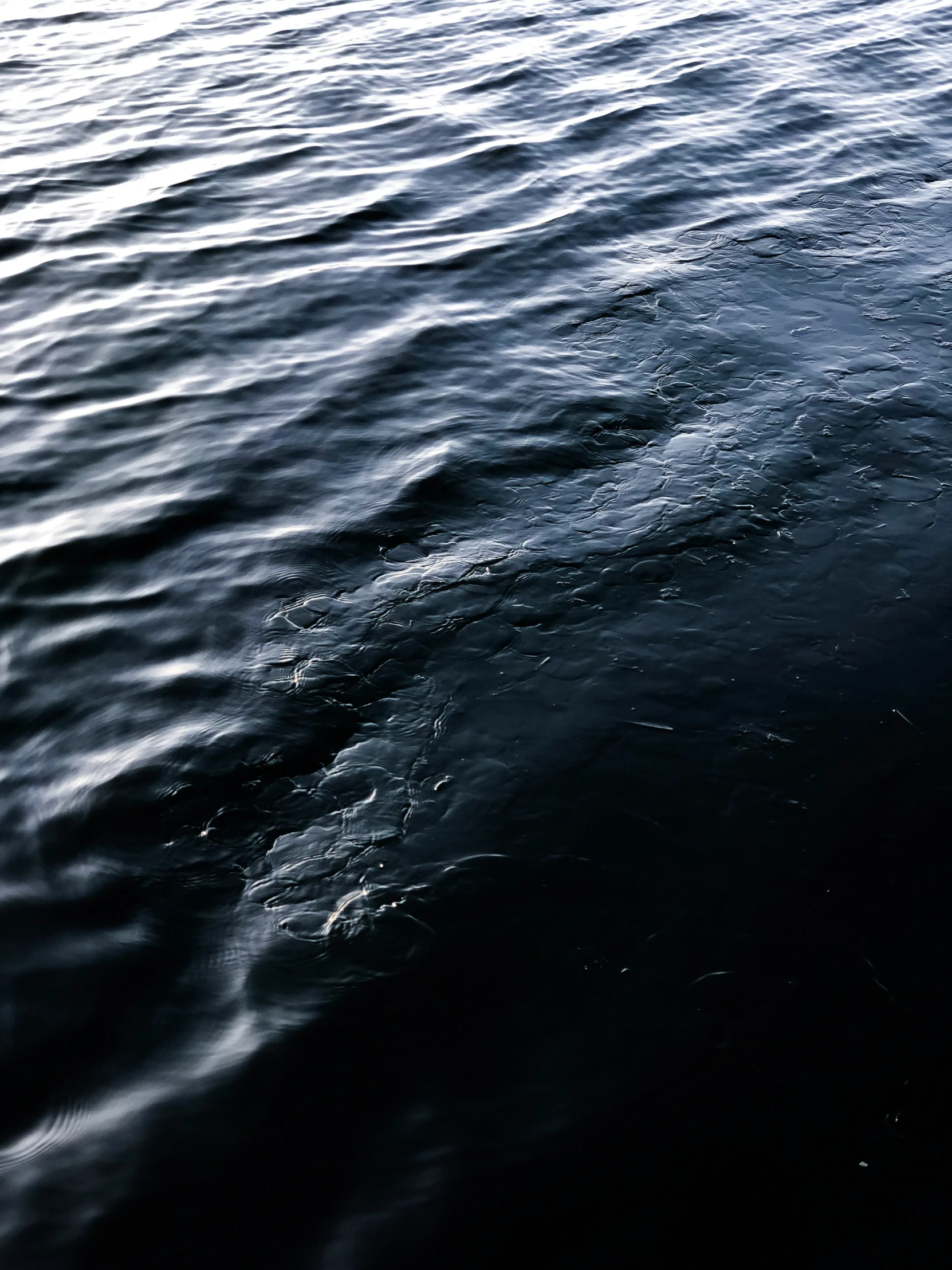 dark blue water with very small waves and the bottom of a boat