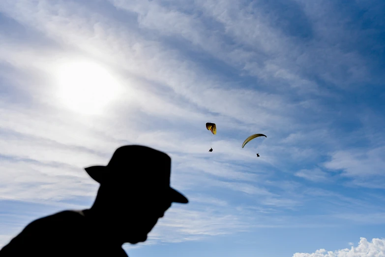 some people and kites in the sky and one is flying