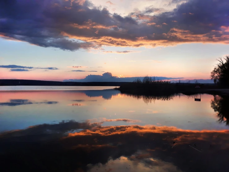 the sun is setting over a calm lake