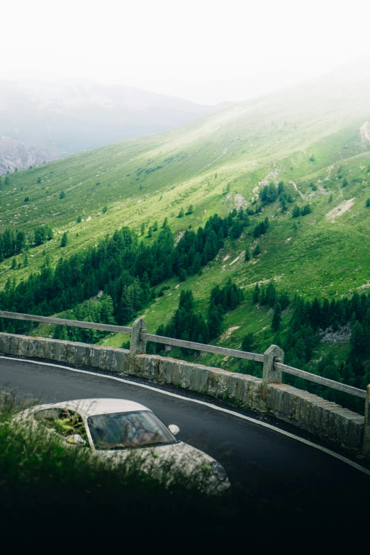 a car sits parked along the road near a rocky wall