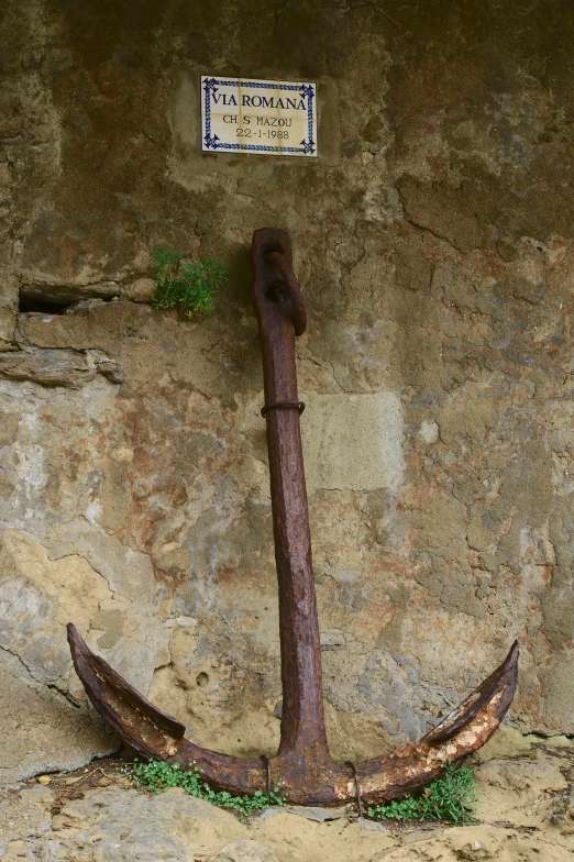 an anchor is leaning against a stone wall