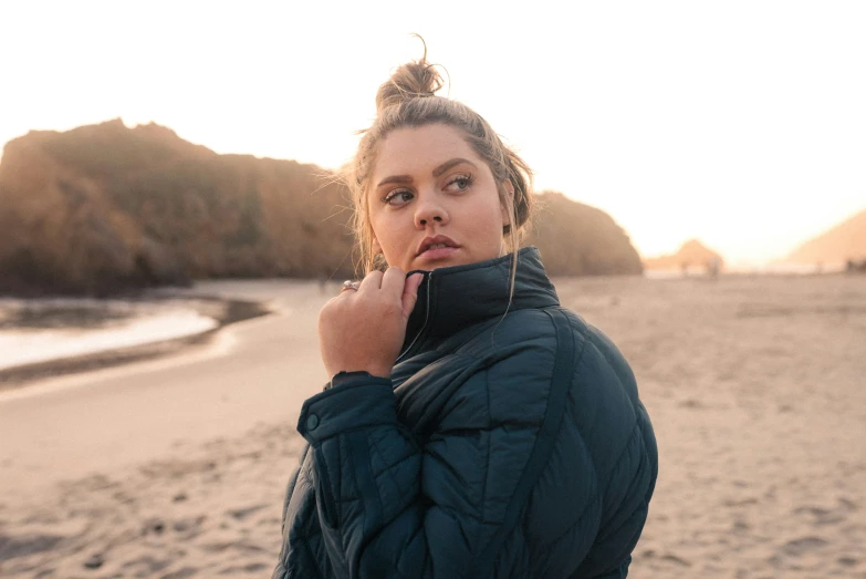 a woman wearing a blue coat at the beach