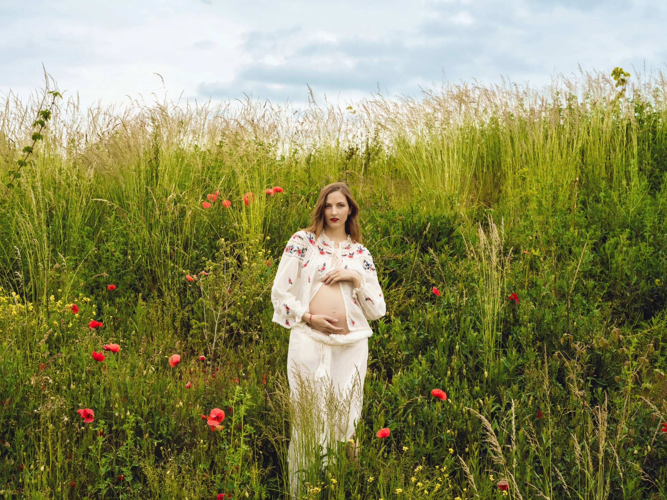 a woman in a field with flowers and her pregnant child