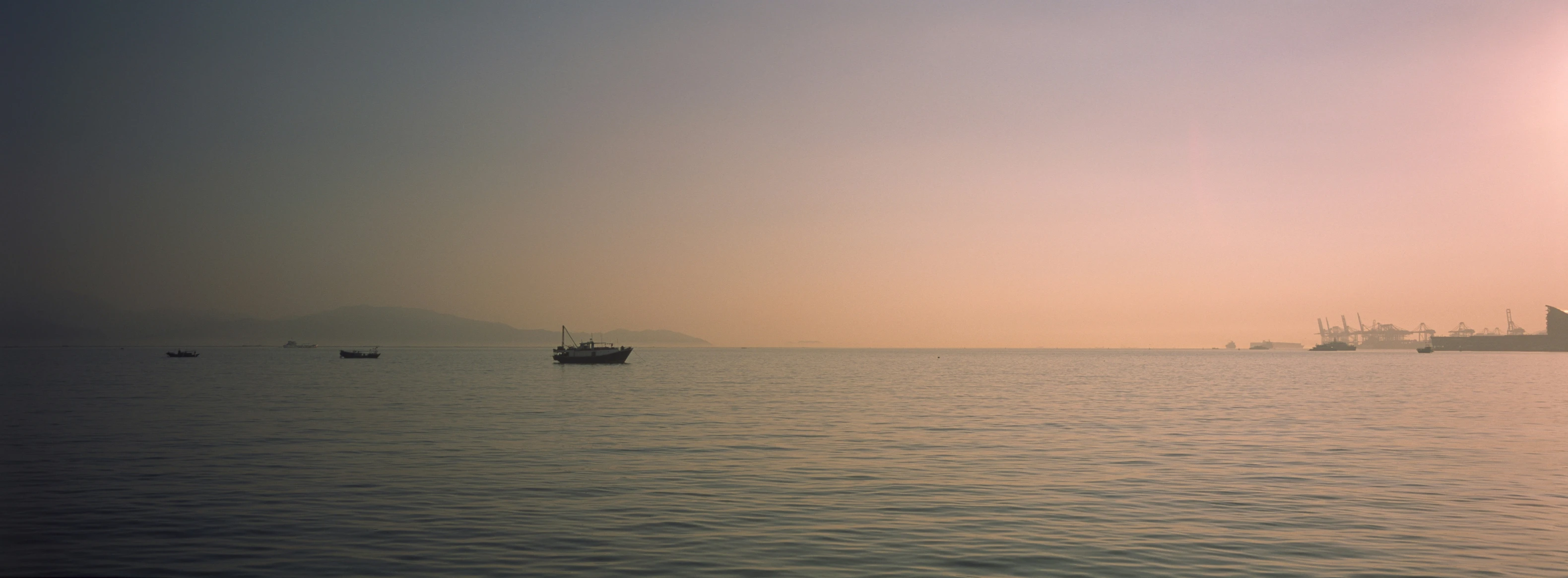 the sun sets over boats in the water