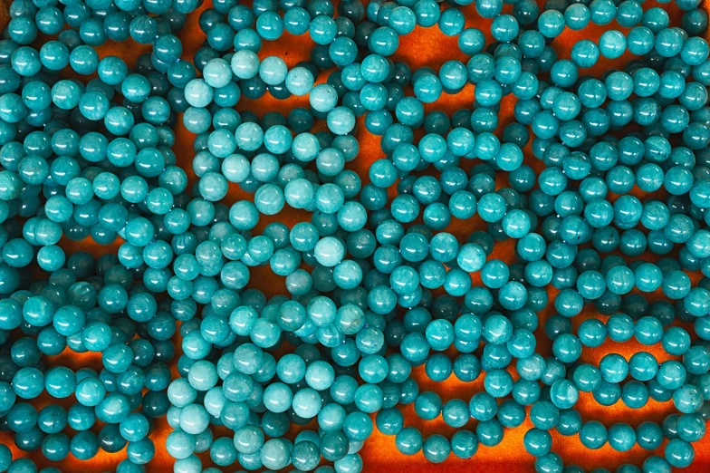 turquoise pearls are in an orange, yellow and orange basket