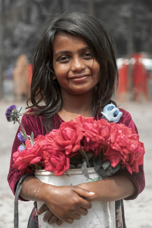 a girl holding flowers smiles while standing in the dirt