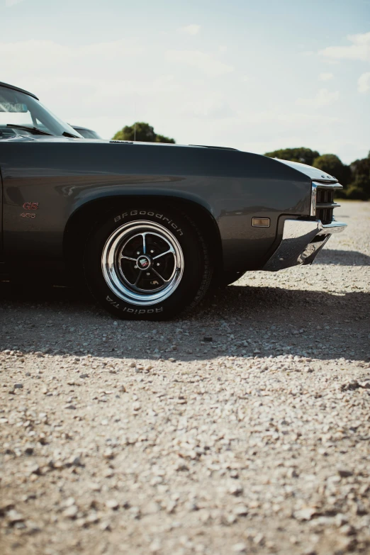 an old black muscle car parked in the dirt