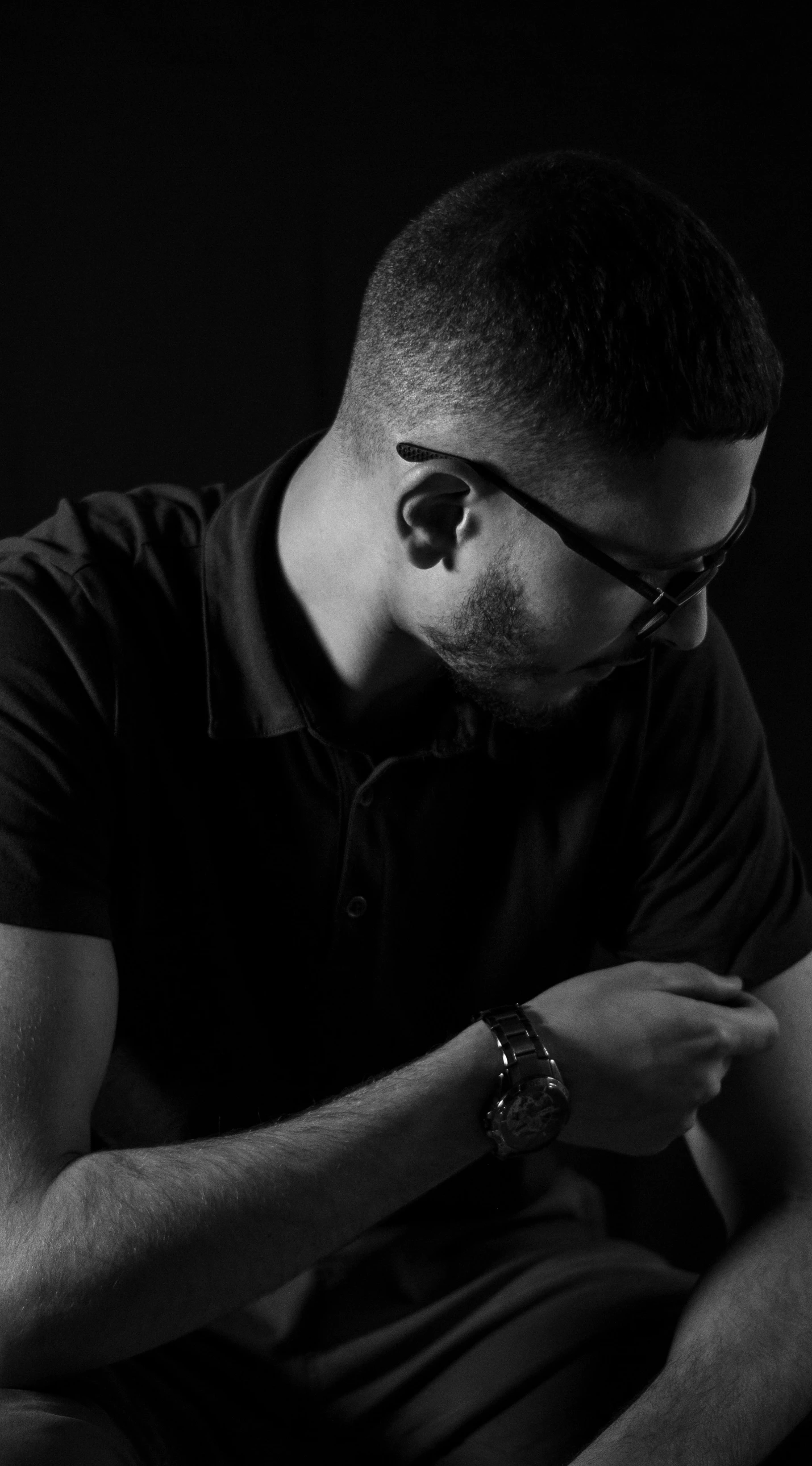 a black and white po of a man sitting down holding his arm